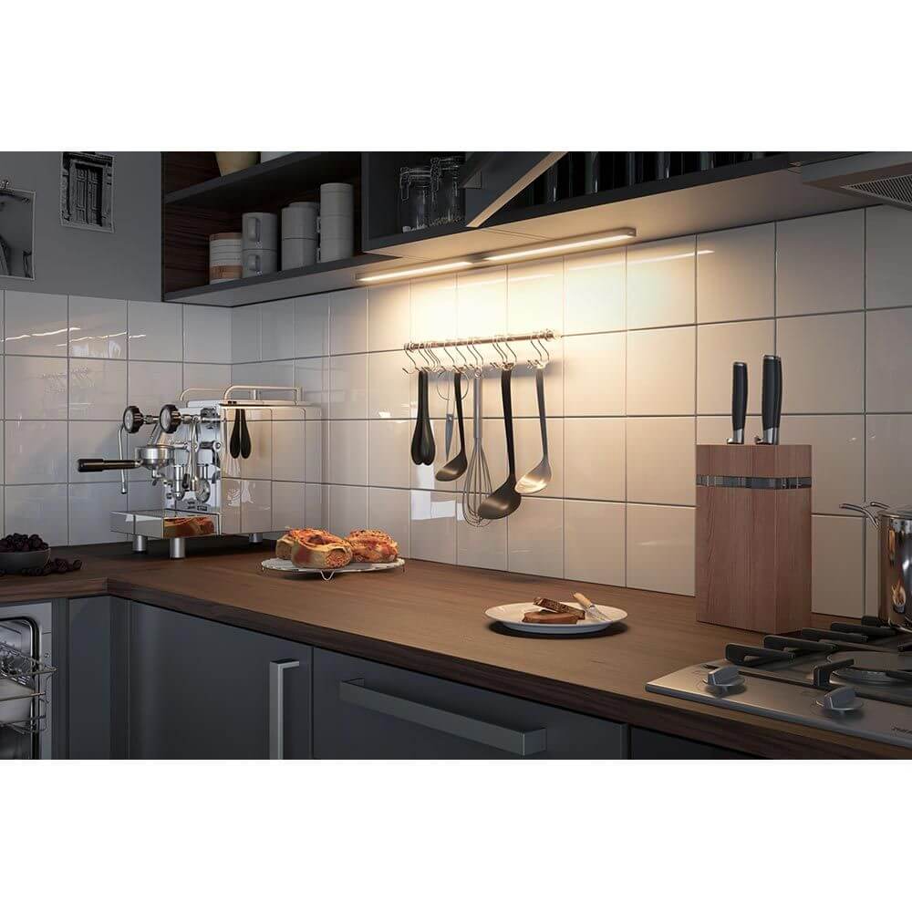 Clever LED Leiste Barre Weiß, Chrom-Matt beleuchtet moderne Küchenarbeitsfläche mit Utensilien und Holzblock.
