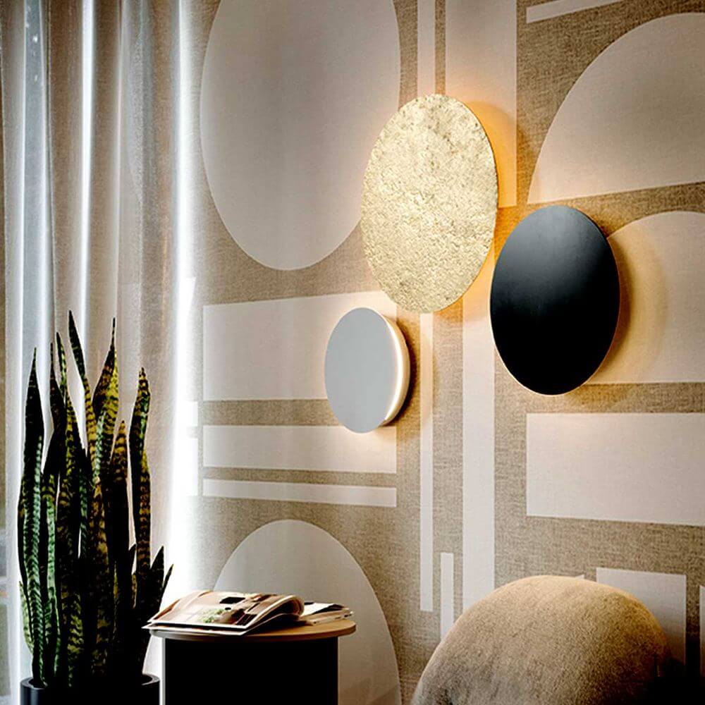 s.luce Lampe murale LED indirecte Cloud & plafonnier sur un mur décoratif avec des plantes et des magazines.