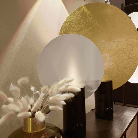 Moderne Raumdekoration mit goldenen und weißen Kreisen sowie einer stilvollen Vase mit getrockneten Pflanzen.