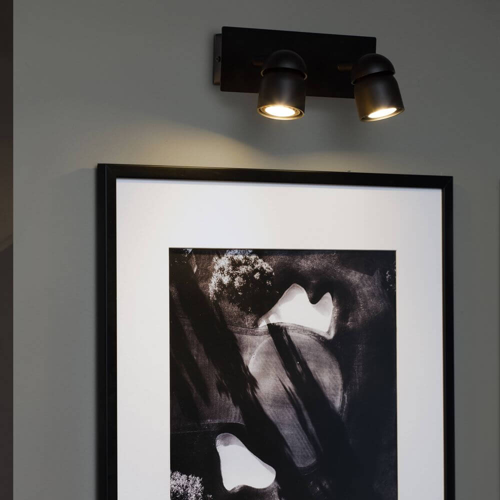 Coco Wandlampe 2-flammig an einer Wand über einem gerahmten Kunstwerk, modernes Design, funktionale Beleuchtung.