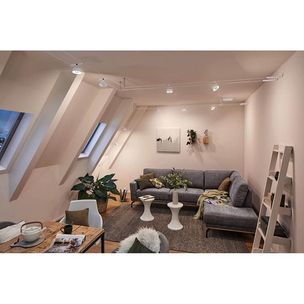 CorDuo LED Seilsystem Circle Einzelspot Weiß-Matt, Chrom in modernem Wohnraum mit Sofa und Pflanzen.