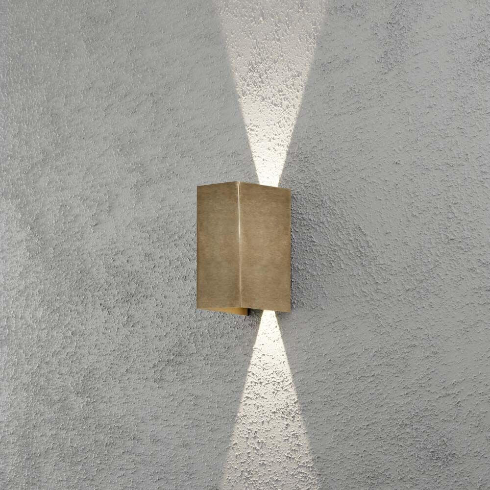 Cremona LED Messing Wandleuchte an grauer Wand strahlt nach oben und unten.
