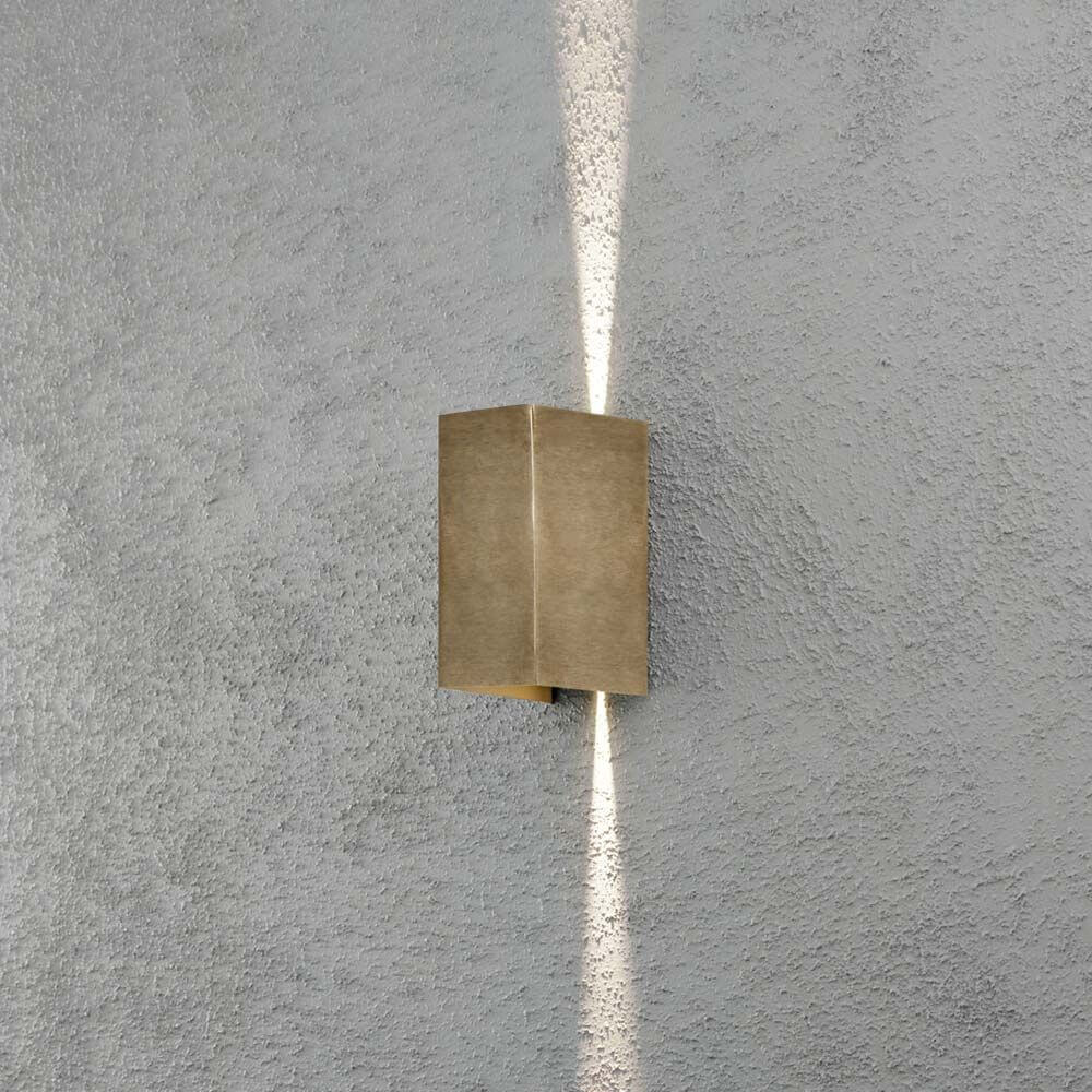 Cremona LED Messing Wandleuchte an einer grauen Wand mit Lichtstrahlen nach oben und unten.