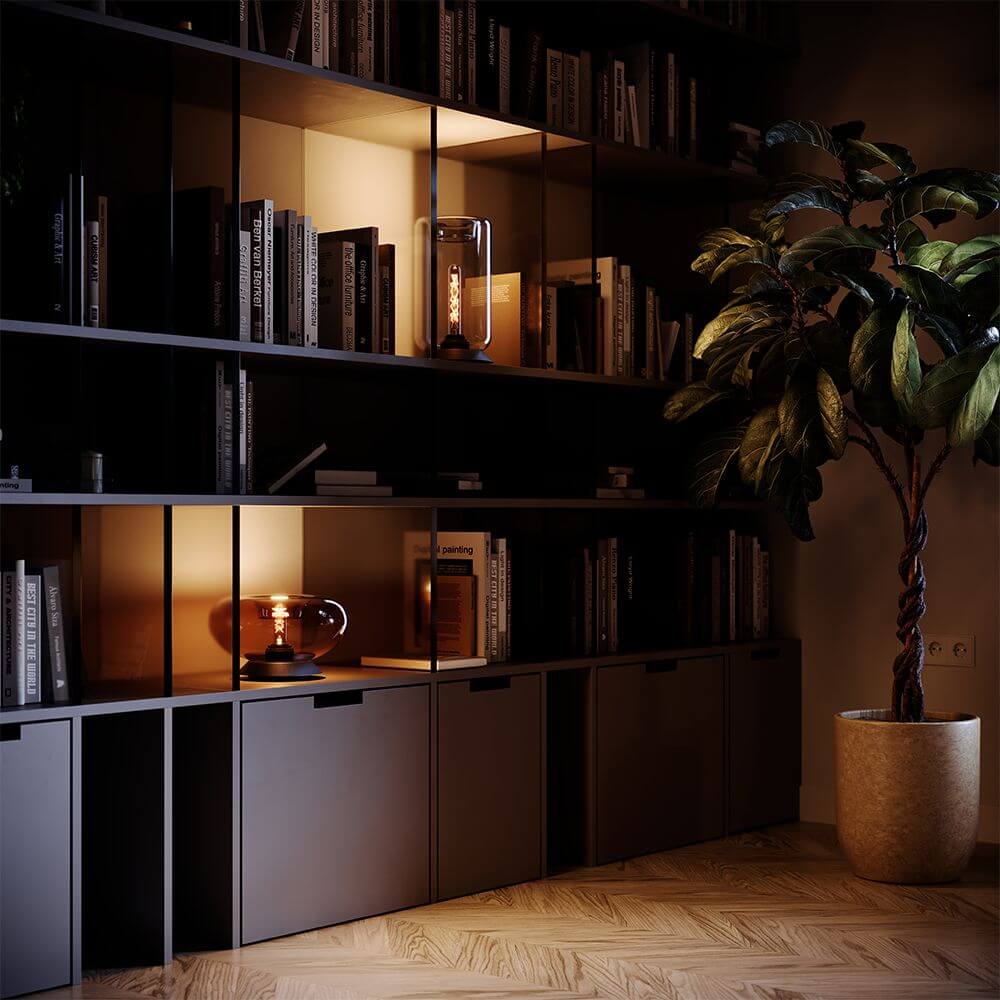 s.luce Cruet E27 Design Tischleuchte Glas mit Schalter auf einem Regal, umgeben von Büchern und Pflanzen.