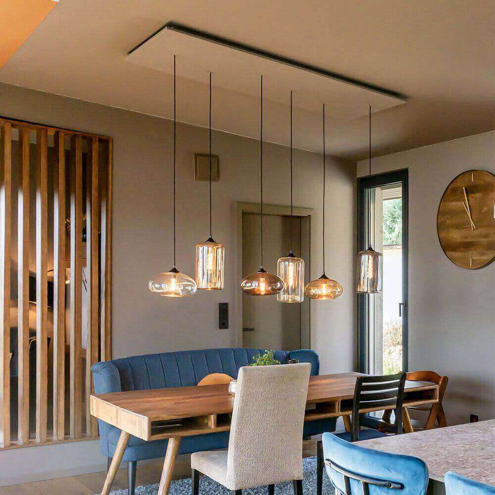 Moderne Esszimmerbeleuchtung mit hängenden Glaskugelleuchten über einem Holztisch und blauen Stühlen.