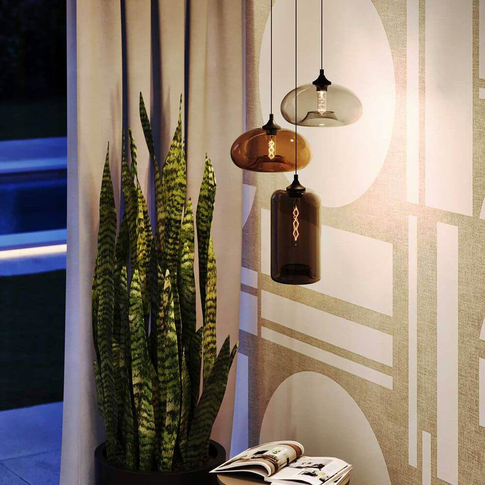 Moderne hängende Lampen über einer Zimmerpflanze in einem stilvollen Innenraum mit grauen Vorhängen.