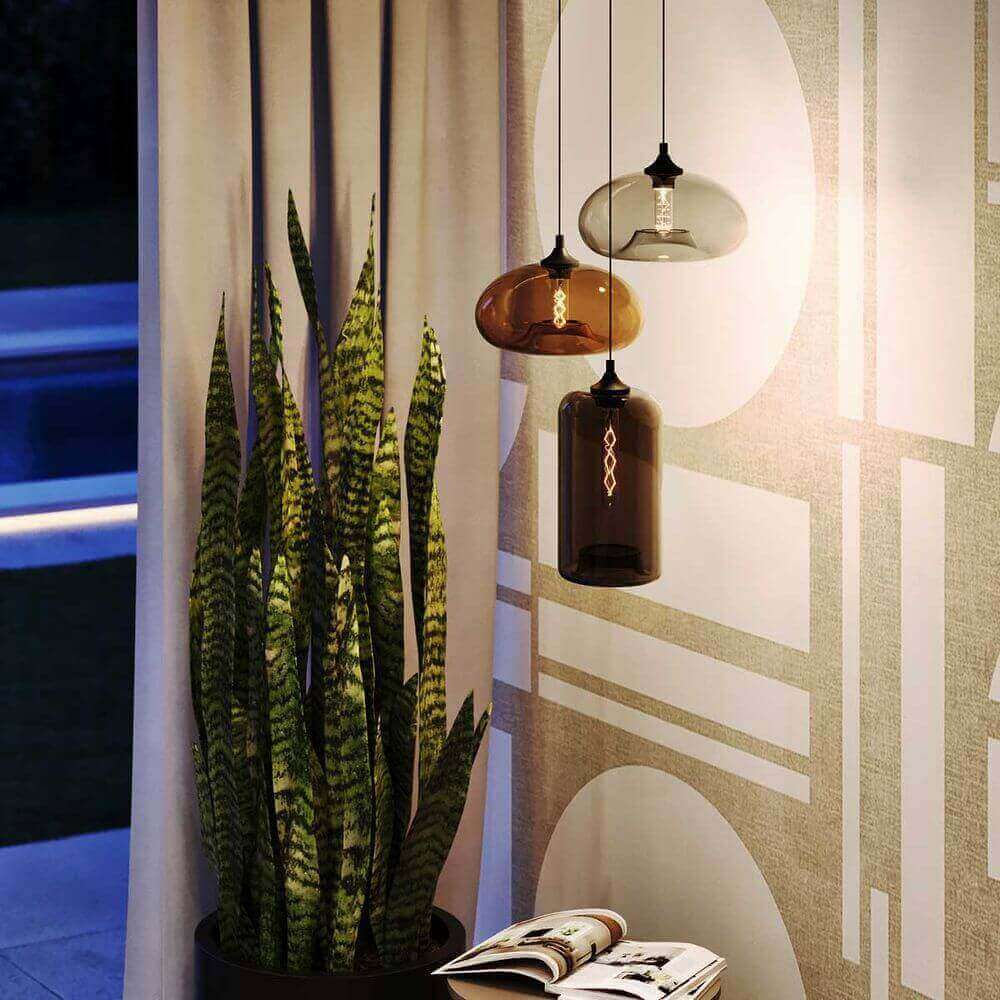 Moderne hängende Lampen über einer Zimmerpflanze in einem stilvollen Innenraum mit grauen Vorhängen.