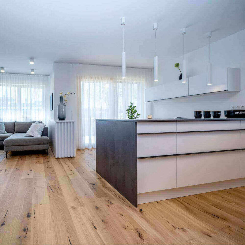 Moderne Küche mit Holzfußboden, eleganter Kücheninsel und gemütlichem Wohnzimmer im Hintergrund.