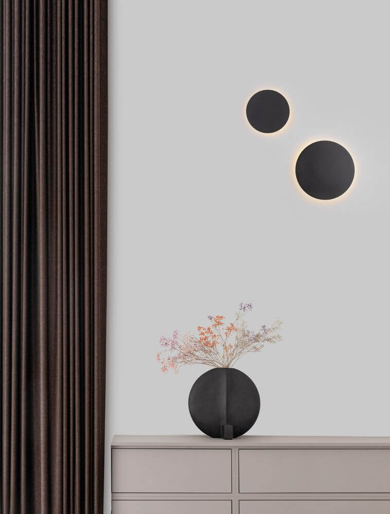 Cyrcle LED Wandleuchte Ø 30cm 3000K an einer Wand mit stilvollem Design und Vasenarrangement.