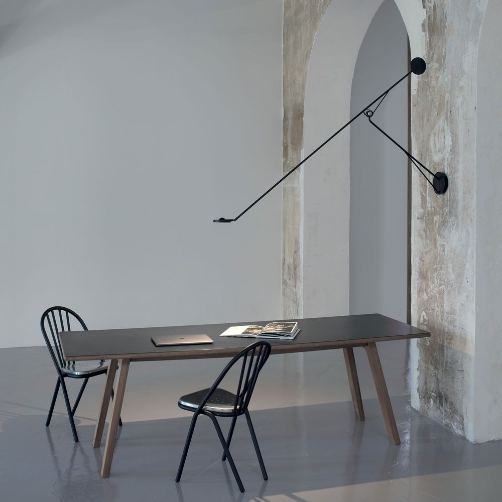 DCWéditions Aaro LED Wandleuchte 160cm schwenkbar neben einem modernen Tisch und Stühlen in einem stilvollen Raum.