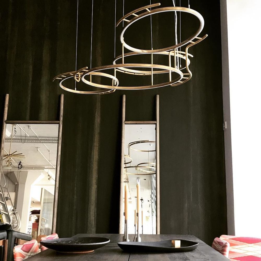 Moderne DCWéditions Broche LED Kronleuchter aus Messing, elegant über einem Tisch installiert.