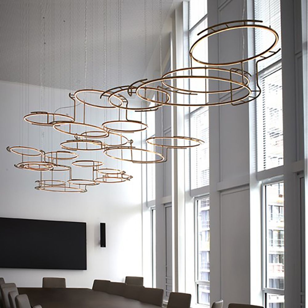 Moderne Messing Kronleuchter mit mehreren kreisförmigen LED-Lichtern in einem eleganten Raum.