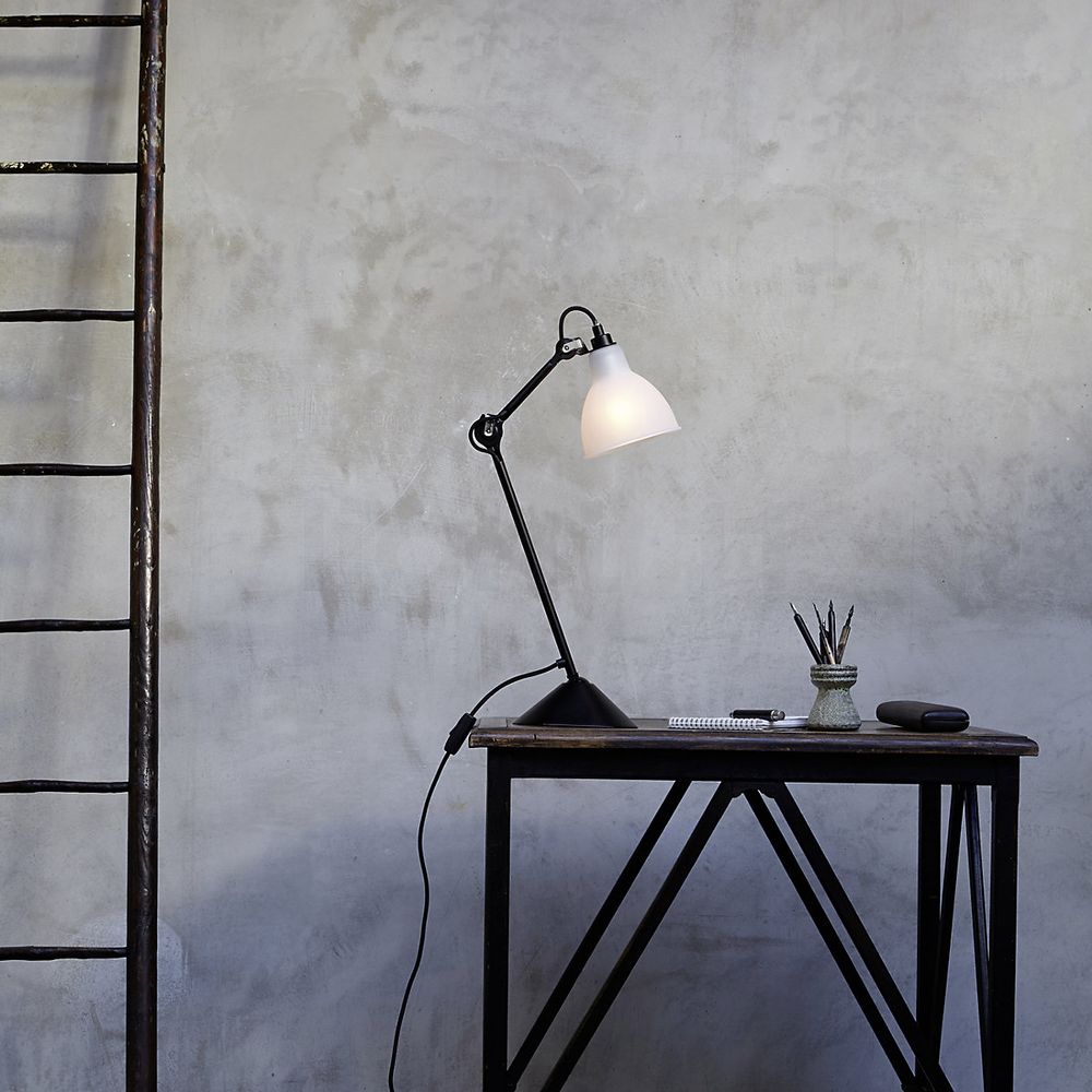 DCWéditions Gras N°205 Tischlampe mit schwenkbarem Schirm auf einem modernen Tisch.