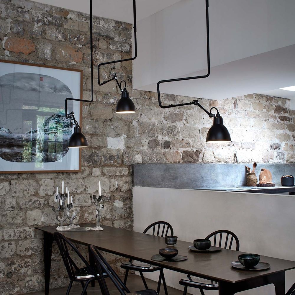 DCWéditions Gras N°312 Deckenlampe im stylishen Essbereich mit Steinwand und minimalistischer Einrichtung.