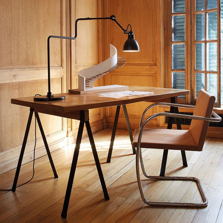 DCWéditions Gras N°317 Tischlampe mit Schirm schwenkbar über einem modernen Holztisch in einem stilvollen Raum.