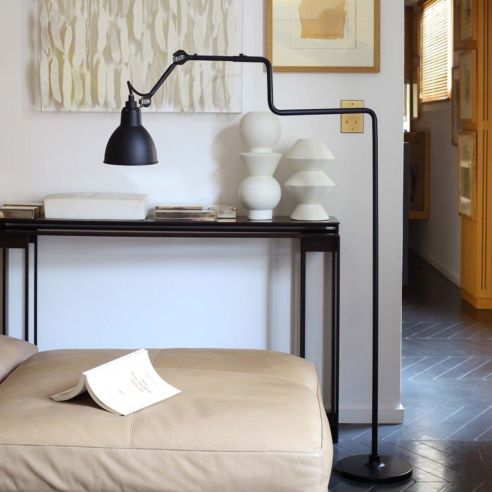 DCWéditions Gras N°411 Stehlampe in Schwarz neben einer Couch, modernes Design für stilvolle Innenräume.