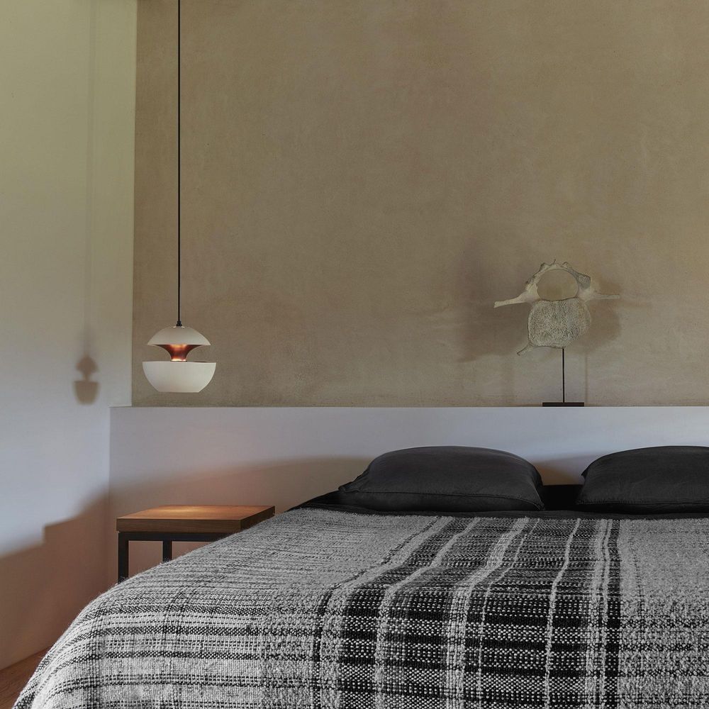 DCWéditions Here Comes The Sun Pendelleuchte über einem modernen Bett mit grauer Bettwäsche und minimalistischer Deko.