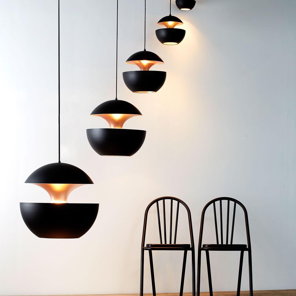 DCWéditions Here Comes The Sun Ø 35cm LED-Pendelleuchte in einer modernen Einrichtung mit schwarzen Stühlen.