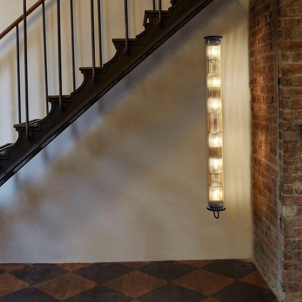 DCWéditions Wandleuchte In The Tube 120-1300 an einer Wand neben einer Treppe, mit 6 Lampen und Borosilikatglas.