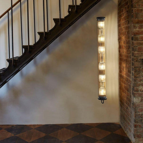 DCWéditions Wandleuchte In The Tube 120-1300 an einer Wand neben einer Treppe, mit 6 Lampen und Borosilikatglas.
