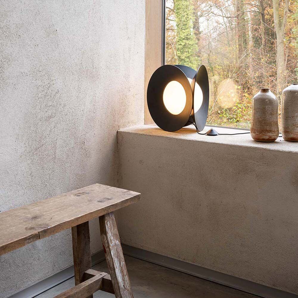DCWéditions Armen LED Tischleuchte Matt-Schwarz auf Fensterbank mit geometrischen Formen.