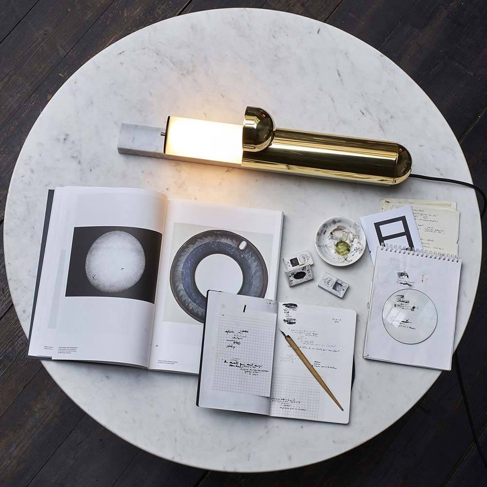 DCWéditions ISP LED Tischleuchte Marmor Messing auf einem Tisch mit Zeitschriften und Notizen.