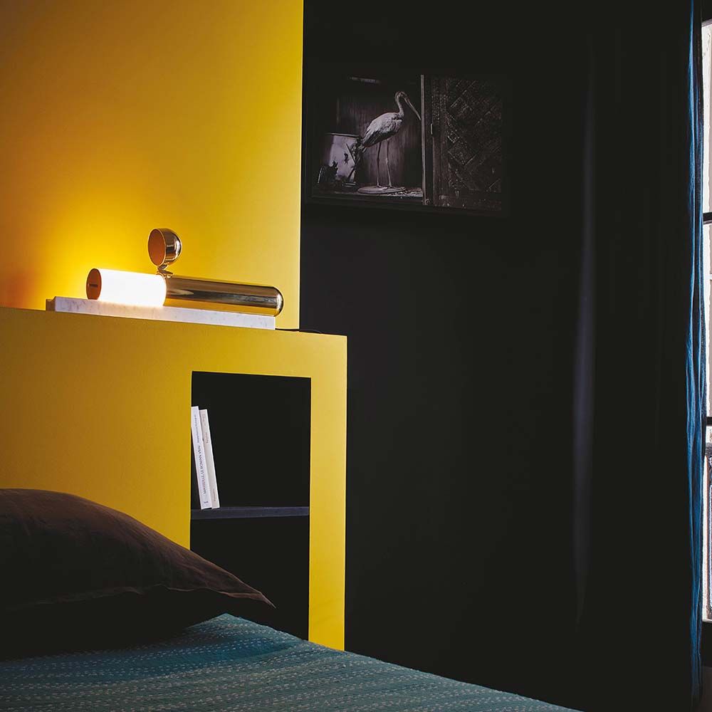 Moderne DCWéditions ISP Tischleuchte aus Messing auf Marmorsockel in einem gelben Schlafzimmer.