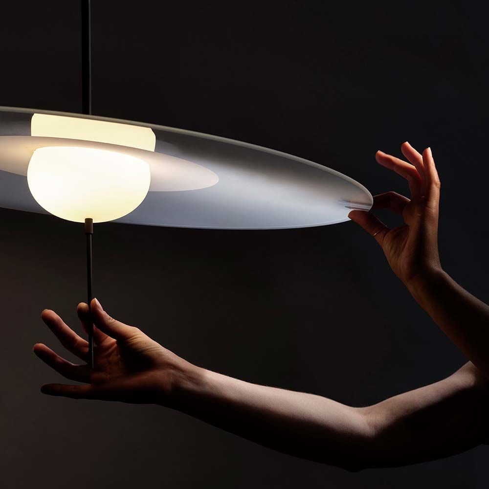 Hand, die die stilvolle DCWéditions Mono LED Hängeleuchte anpasst, um die Lichtintensität zu variieren.