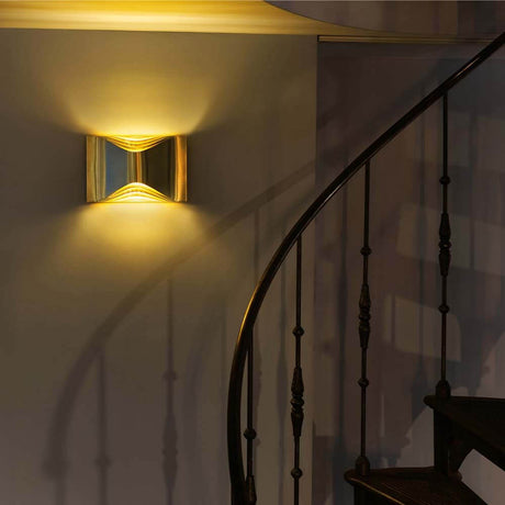 DCWéditions Respiro LED-vegglampe Gold på en vegg, varmt lys, moderne design.