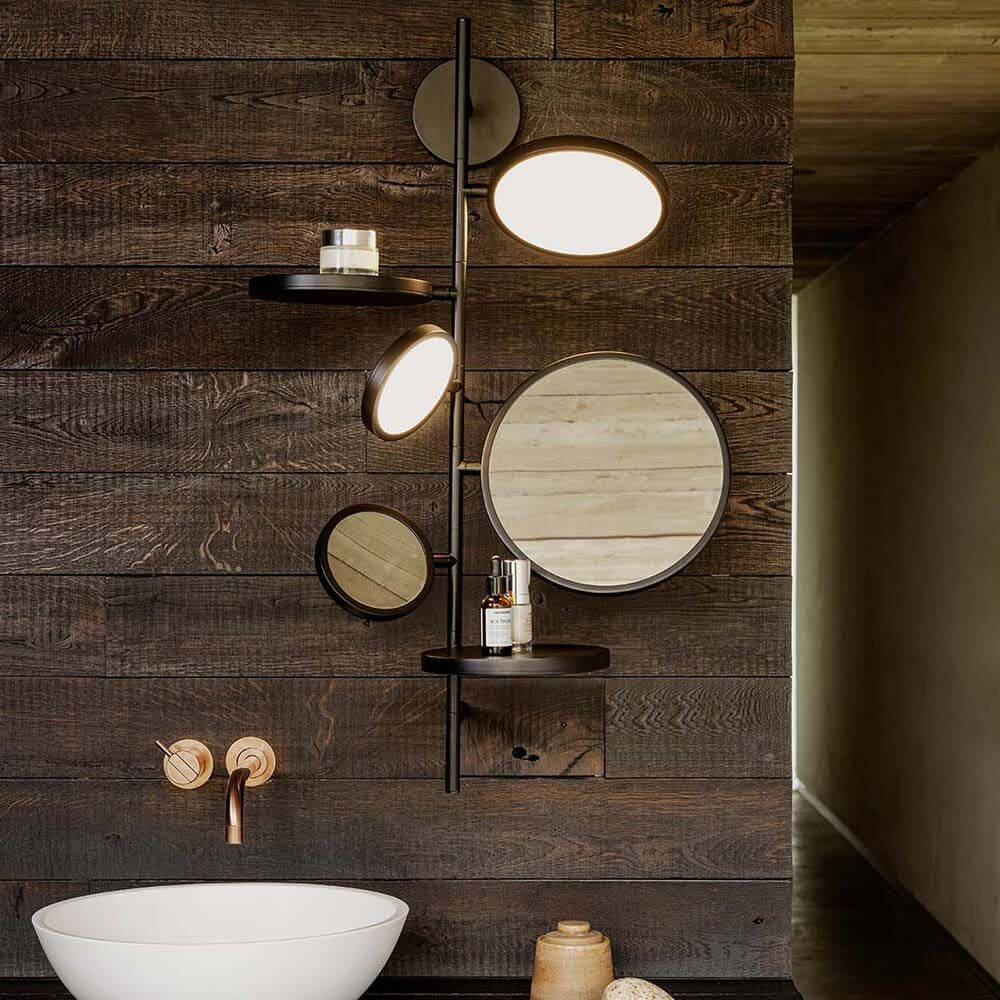 DCWéditions Tell Me Stories LED Wandleuchte & Spiegel mit zwei Spiegeln und Ablagen an einer Holzwand.