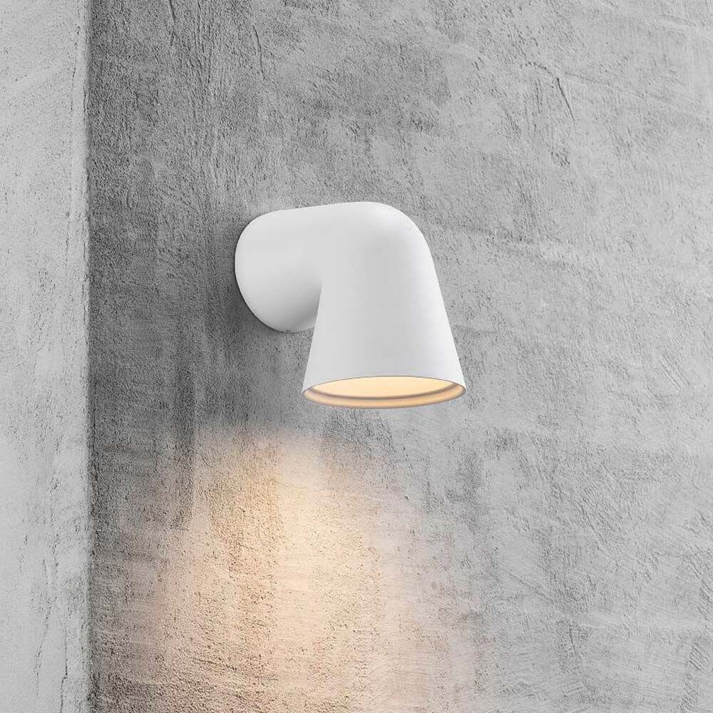 Außen-Wandleuchte Front Single IP44 Weiß an einer Wand montiert, strahlt warmes Licht aus.