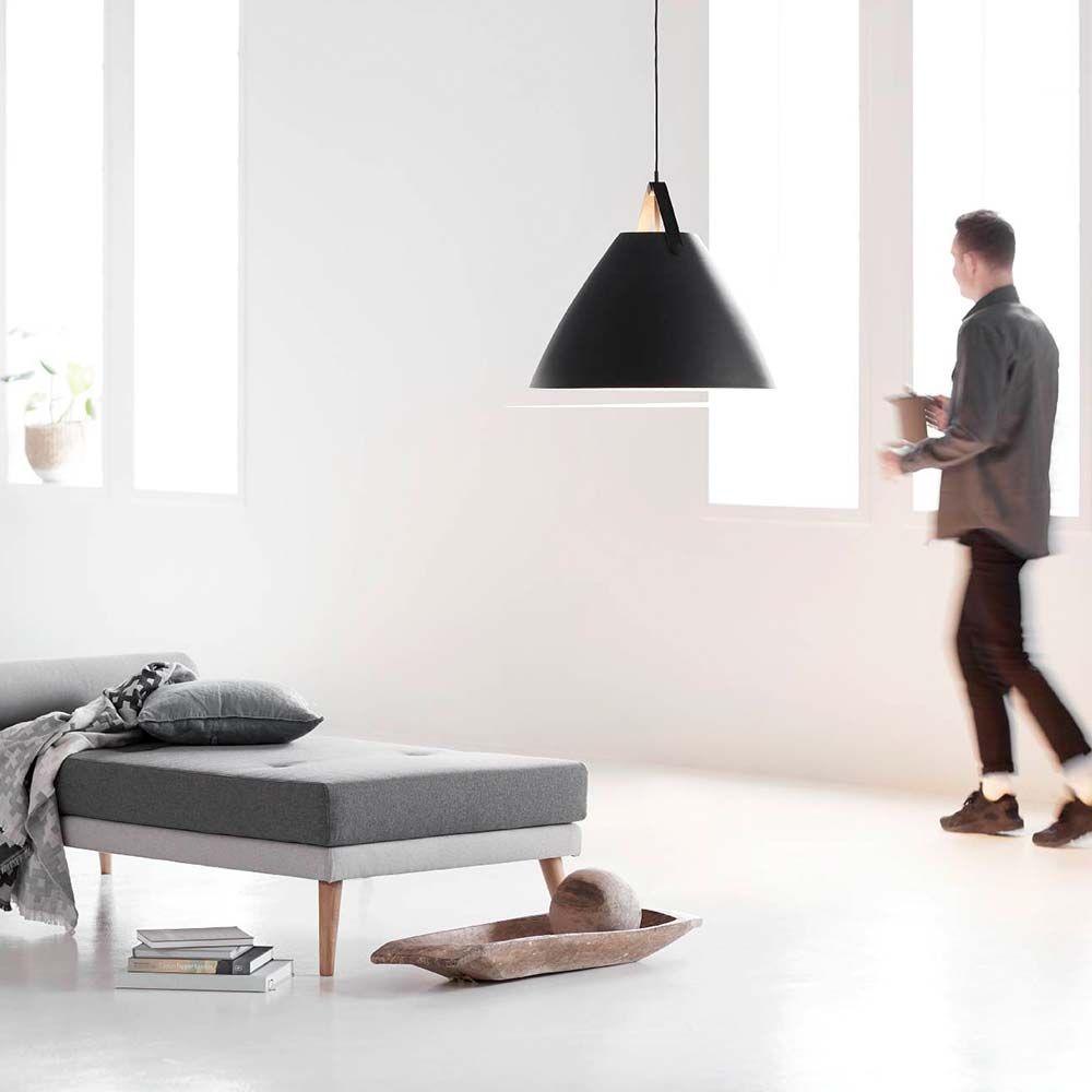 Pendellampe Strap 68 Schwarz über einem modernen Sofa in einem hellen Raum mit großen Fenstern.