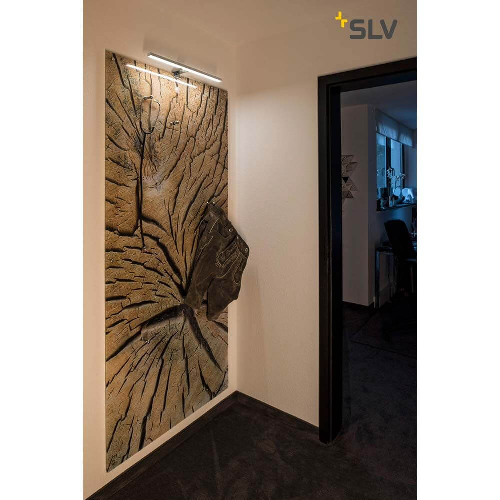 DORISA LED Spiegelleuchte lang chrom 4000K IP44 an einer Wand mit Kunstwerk im Hintergrund.