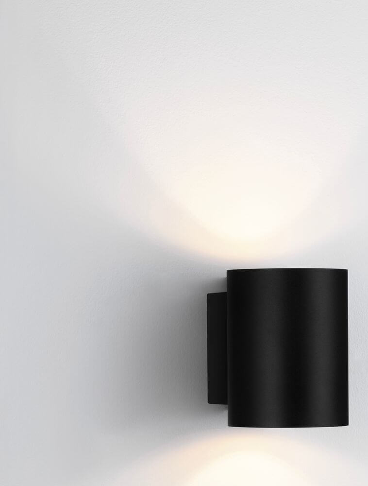 Dazle Wandleuchte Ø 8cm in elegantem Schwarz an der Wand montiert, mit sanftem Lichtschein.