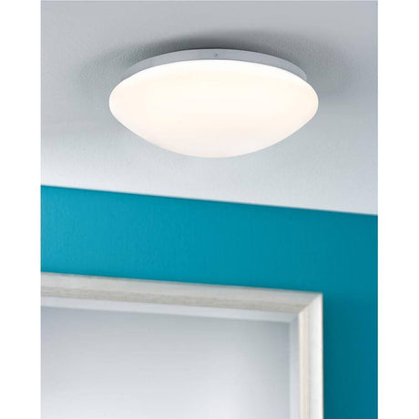 Plafonnier LED Leonis rond 9,5W blanc chaud IP44 au plafond dans une pièce moderne aux murs bleus.
