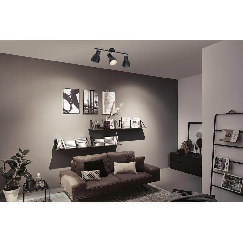 Deckenstrahler Davy 3-flammig Schwarz in modernem Wohnraum mit gemütlichem Sofa und stilvollen Regalen.