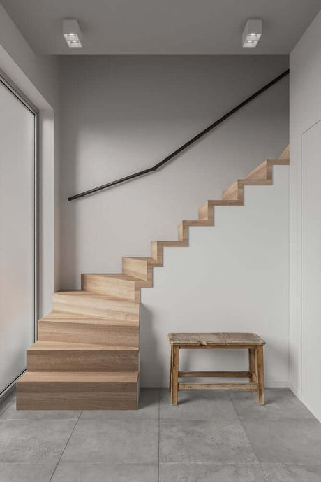 Escalier moderne avec marches en bois et design minimaliste à l’intérieur, éclairé par le projecteur de plafond Ethan 2 spots.