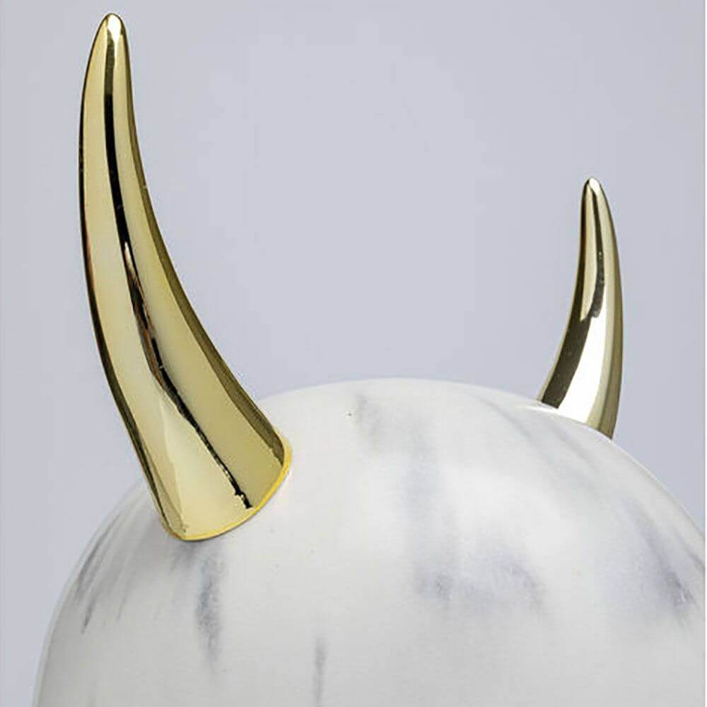 Design Tischleuchte Horn mit goldenen Hörnern auf einem weißen, marmorierten Lampenfuß.