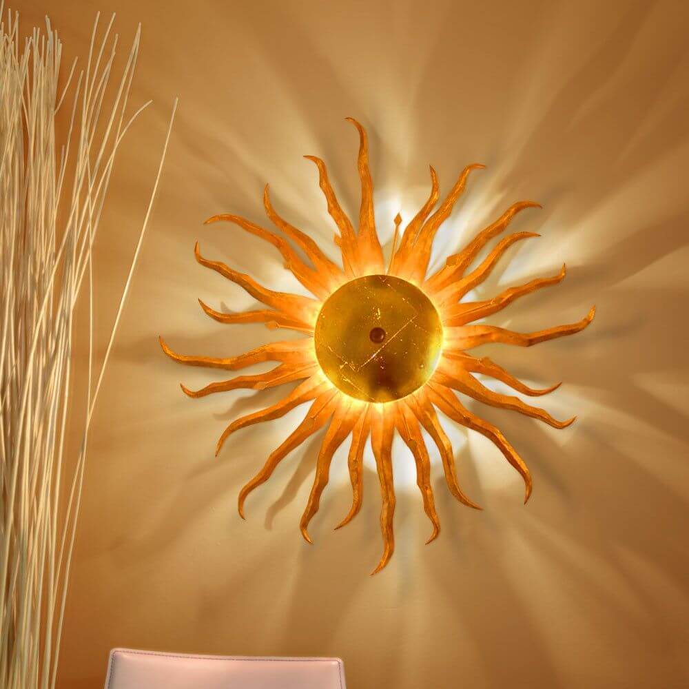 s.luce Diator XL håndsmedet sol i rust- & guldfarver på væggen med fascinerende lyseffekter.