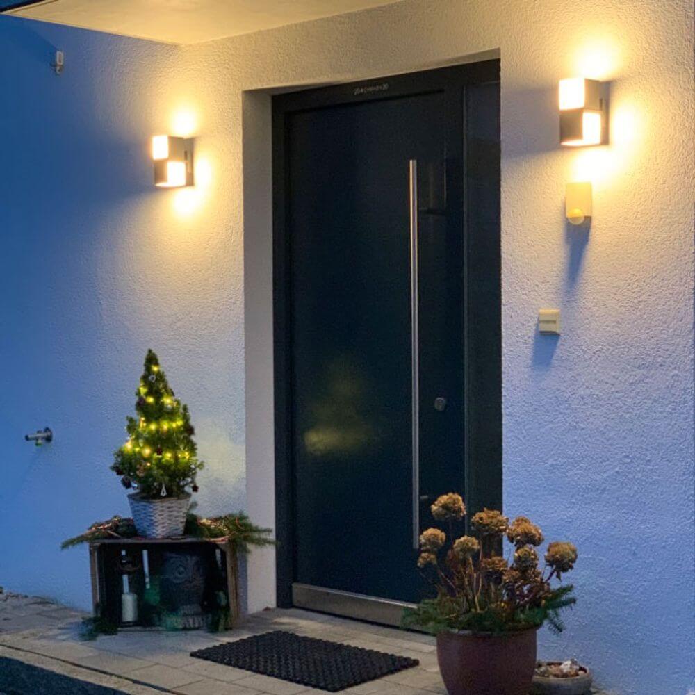 Drehbare LED-Außenwandleuchte Cuba IP54 Anthrazit beleuchtet den Eingangsbereich mit festlicher Dekoration.