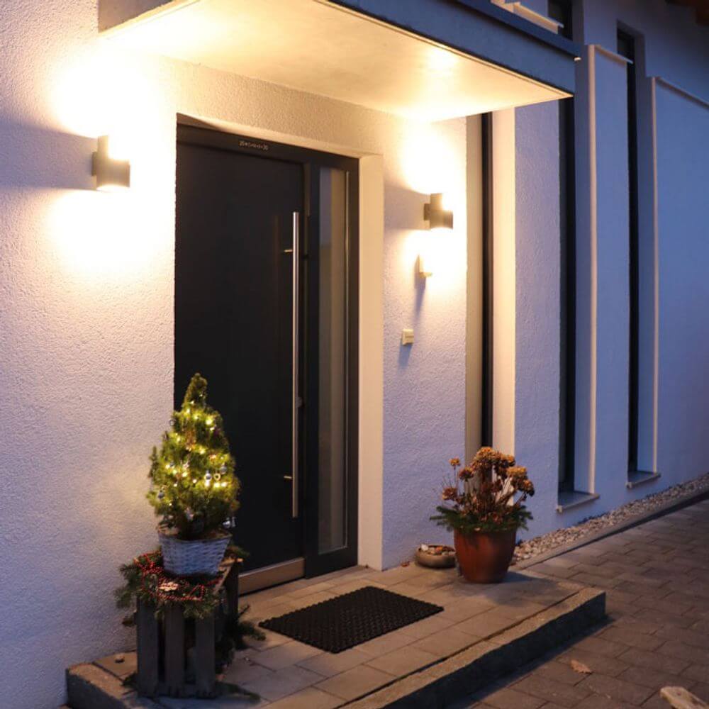 Drehbare LED-Außenwandleuchte Cuba IP54 Anthrazit erhellt den Eingangsbereich eines modernen Hauses.