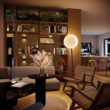 s.luce Dreibein-Stehleuchte Orb Tripod 160cm mit Glaskugel steht im stilvollen Wohnzimmer.