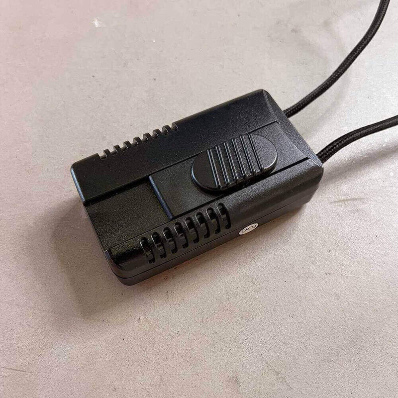 Schwarzer elektrischer Schalter mit glänzender Oberfläche auf grauem Untergrund, ideal für verschiedene Elektroprojekte.