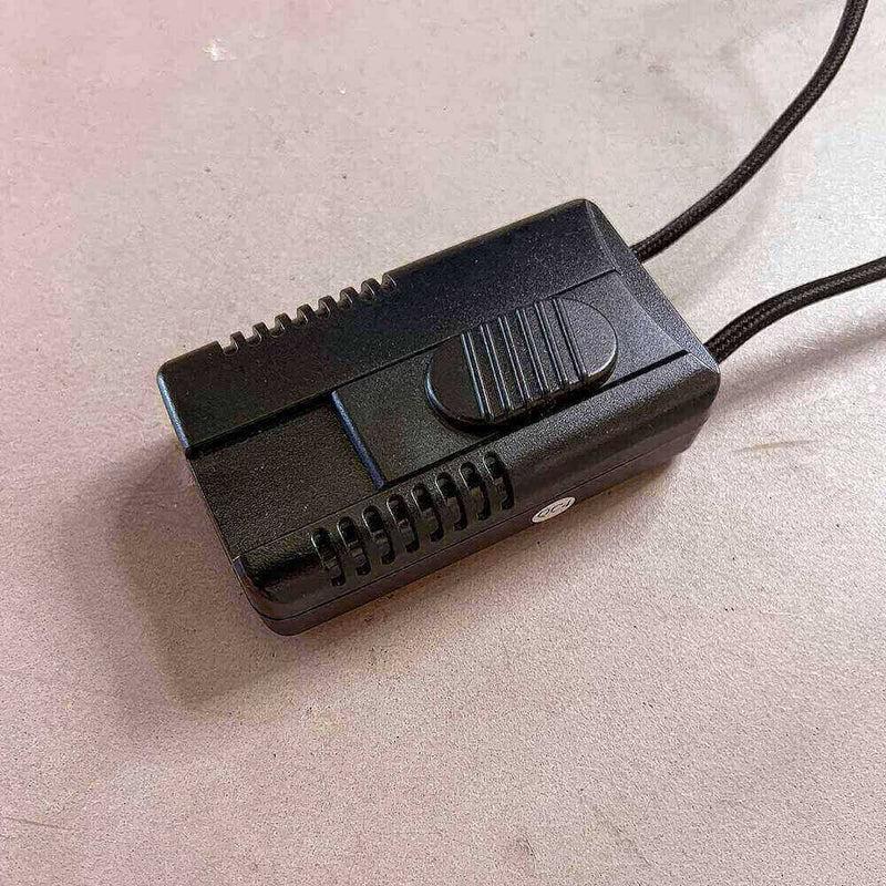 Schwarzer elektrischer Schalter mit glänzender Oberfläche auf grauem Untergrund, ideal für verschiedene Elektroprojekte.