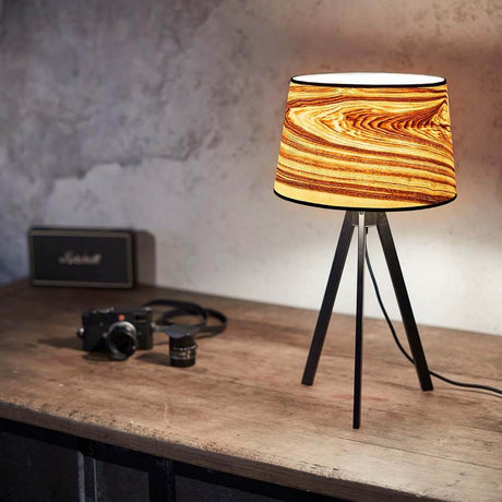 Dreibeintischlampe Attica 60cm Esche mit konischem Schirm aus Echtholzfurnier auf einem Tisch.