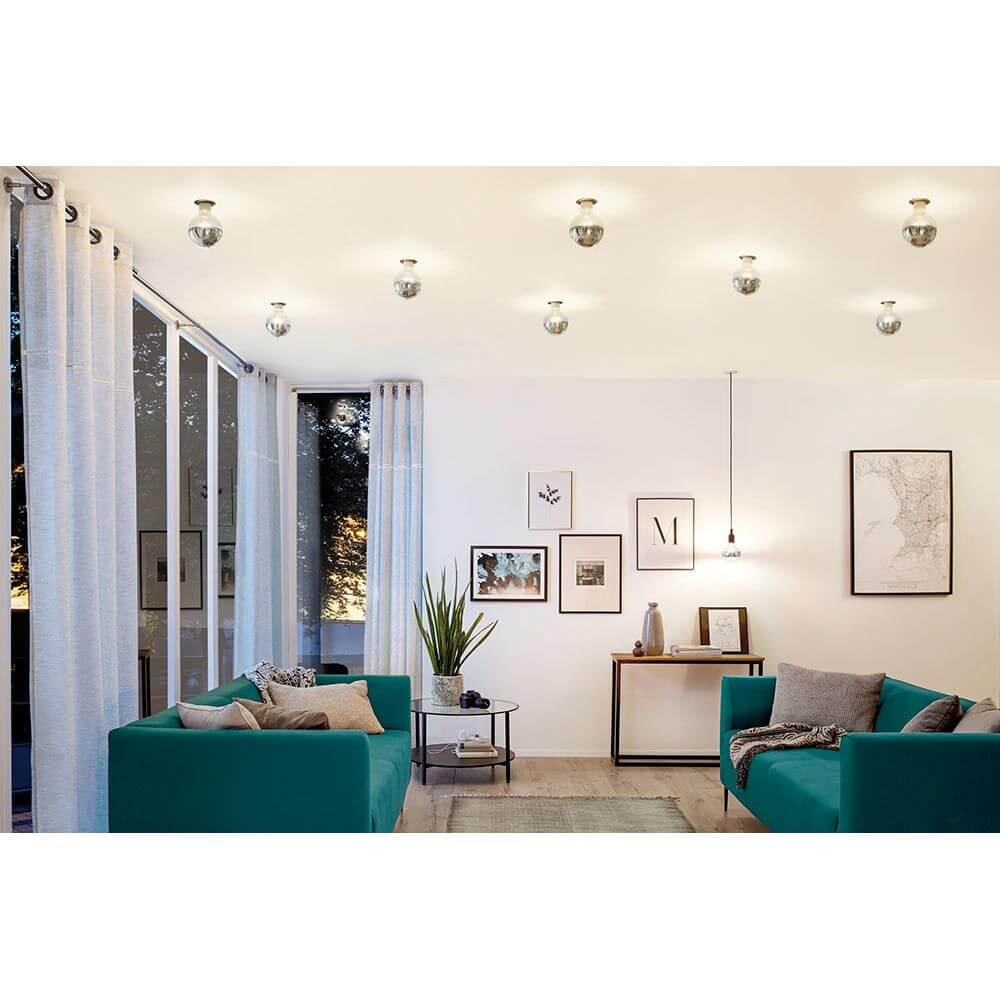 Modernes Wohnzimmer mit E27 4,8W LED Kopfspiegel in warmweißem Licht, stilvoll mit grünen Sofas und Kunstwerken.