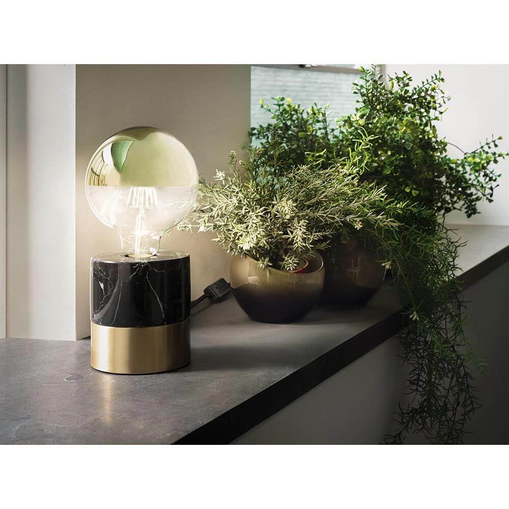 E27 6,5W LED Globe Kopfspiegel 2700K Dimmbar Gold auf einem Tisch mit Pflanzen.