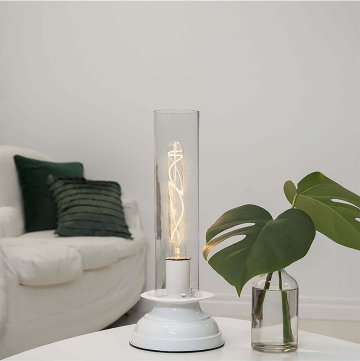 E27 Filament LED Soft Glow 2200K in einer modernen Tischlampe mit Pflanzen im Hintergrund.