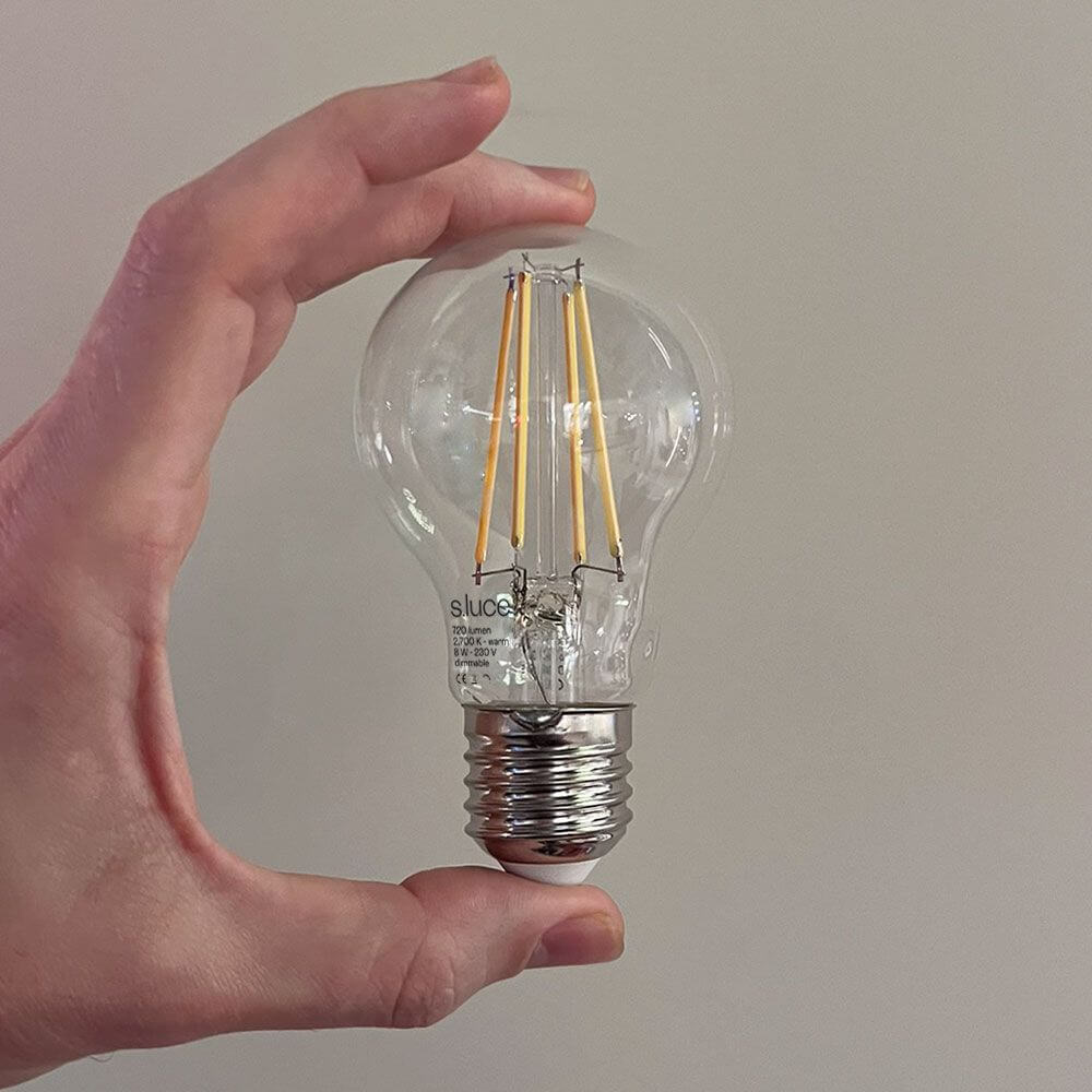 s.luce E27 LED Warmweiß 2700K 720lm 8W Dimmbar CRI 90 in Hand gehalten, klare Glaskonstruktion, energiesparend.