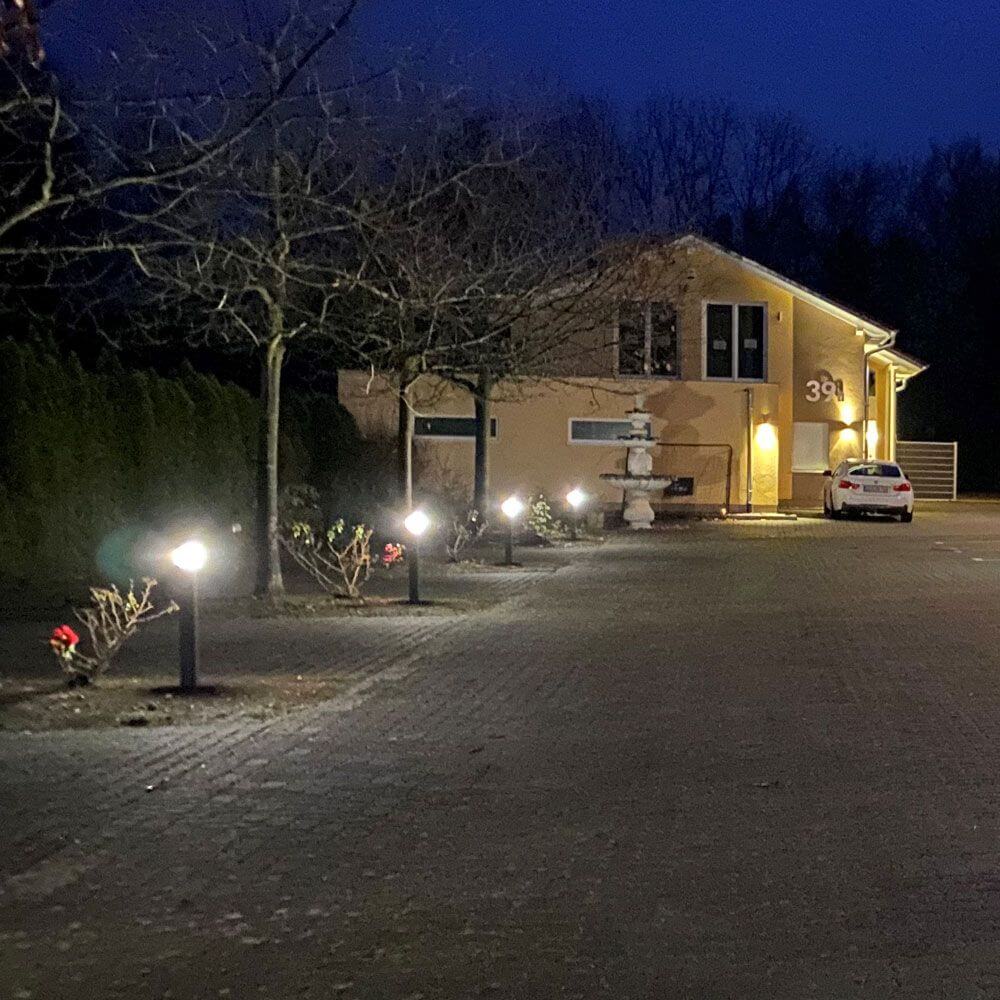 Beleuchteter Gartenweg mit eckigen Pollerleuchten bei Nacht, schöne Atmosphäre und modernes Design.